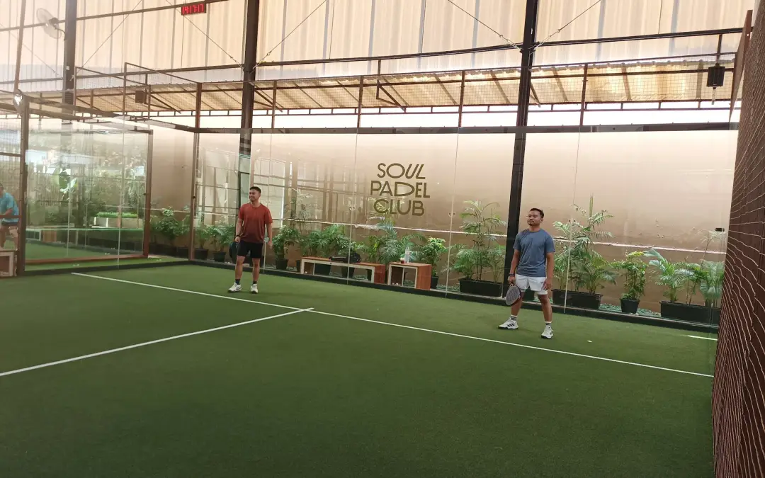 Players on a green court with the Soul Padel Club sign on the back wall